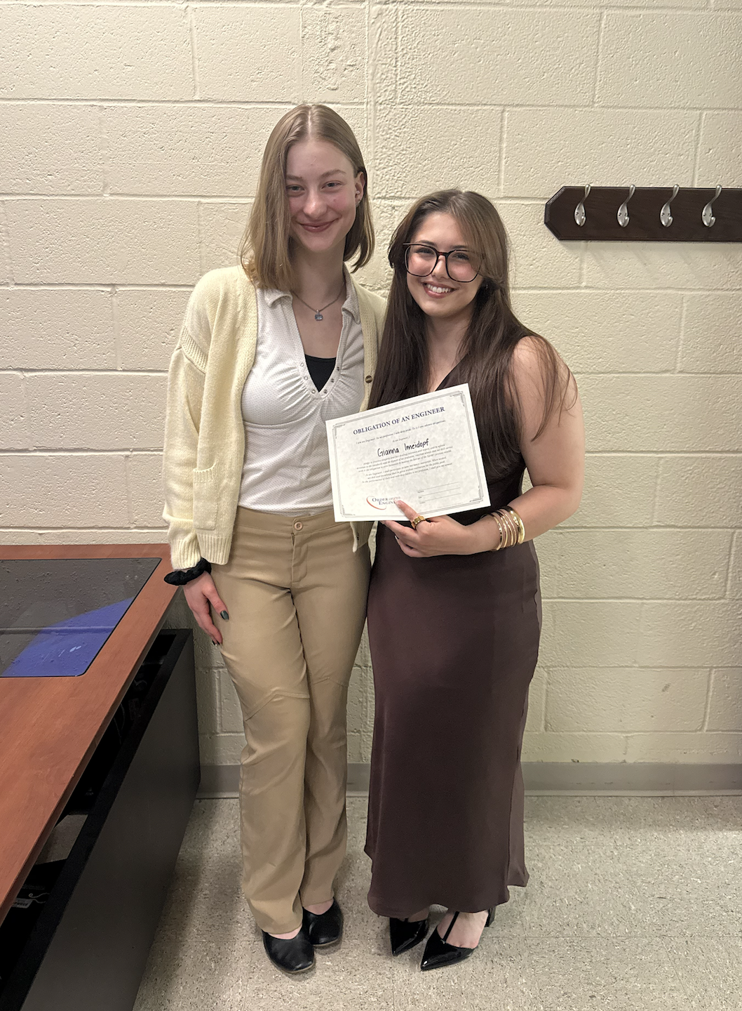 Gianna holding her Engineering Ring Ceremony certificate with a friend